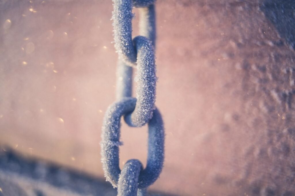 Detailed view of a frosty metal chain with icy surface in winter atmosphere.